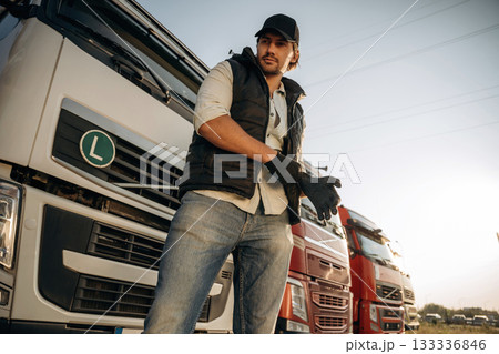 Getting ready for a work, wearing gloves. Truck driver is near the transport outdoors 133336846