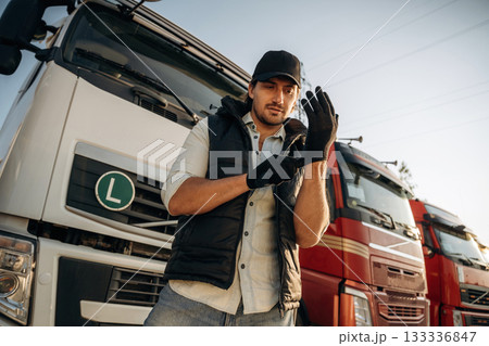 Getting ready for a work, wearing gloves. Truck driver is near the transport outdoors 133336847