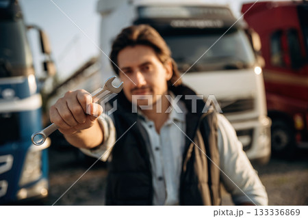 Tool in hand. Truck driver is near the transport outdoors Tool in hand. Truck driver is near the transport outdoors 133336869