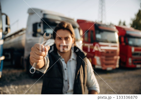 Tool in hand. Truck driver is near the transport outdoors Tool in hand. Truck driver is near the transport outdoors 133336870