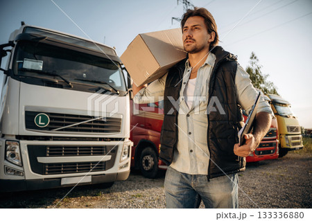 Delivery is on the way, with box. Truck driver is near the transport outdoors 133336880