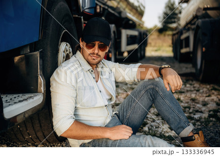 Sitting on the ground. Truck driver is near the transport outdoors Sitting on the ground. Truck driver is near the transport outdoors 133336945