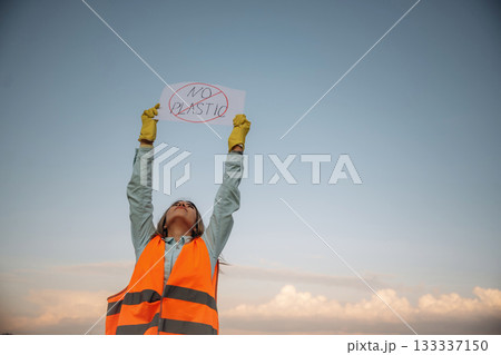 'No plastic' sign in hands. Woman volunteer is against trash pollution outdoors 133337150