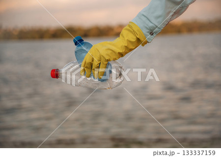Trash pollution. Close up view of female volunteer that is holding plastic bottle. 133337159