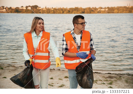 A volunteers collects garbage on a muddy beach A volunteers collects garbage on a muddy beach 133337221