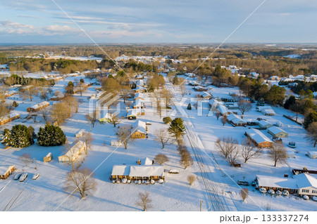 Suburban area blanketed in snow, American village highlighting homes trees on clear winter day 133337274