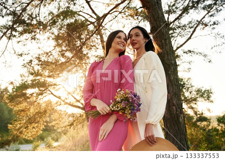 Front view, standing and posing. Lovely lesbian couple are together outdoors in nature 133337553