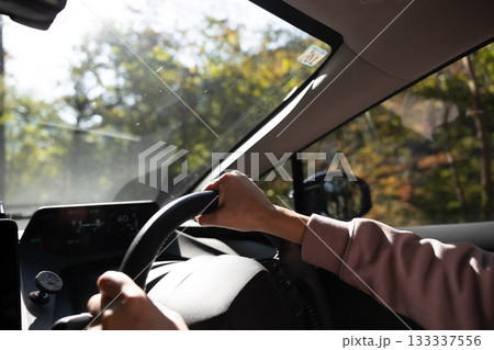 秋の山道を運転している男性の手元 133337556