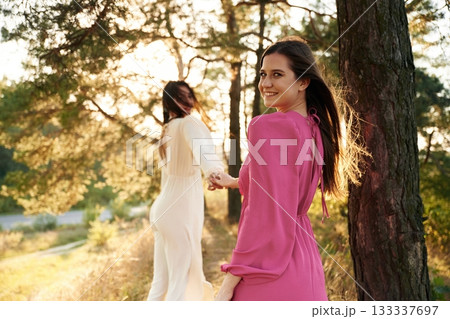 Woman is want to go, with bouquet of flowers. Lovely lesbian couple are together outdoors in nature Woman is want to go, with bouquet of flowers. Lovely lesbian couple are together outdoors in nature 133337697