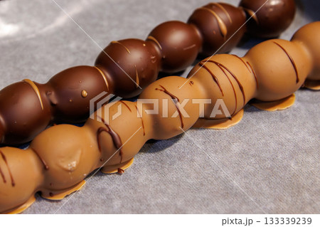 Closeup of two milk and dark chocolate coated grape dessert skewers at a festive christmas or advent market. 133339239