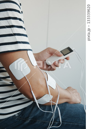 a man using a portable electrotherapy device 133339620