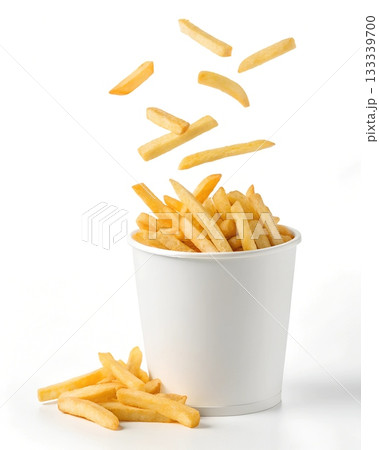 Golden french fries spilling out of a white cup with some falling from above Golden french fries spilling out of a white cup with some falling from above 133339700