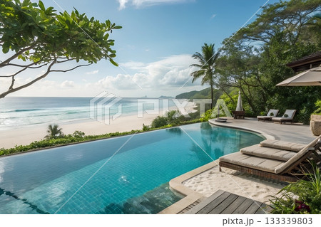Luxury infinity pool overlooks pristine tropical beach with turquoise ocean waves and lush green vegetation Luxury infinity pool overlooks pristine tropical beach with turquoise ocean waves and lush green vegetation 133339803