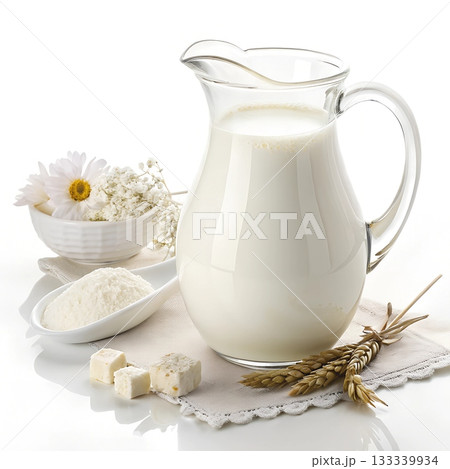 A glass pitcher filled with fresh milk sits beside white flowers cheese cubes and a spoon of milk powder 133339934