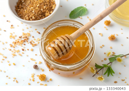 Golden honey in a glass jar with a wooden dipper bee pollen and small flowers 133340043