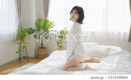 朝の光の中で膝立ちする若い女性のライフスタイルポートレート 133340664