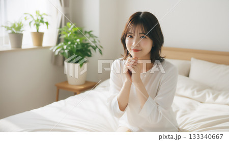 朝の光の中で膝立ちする若い女性のライフスタイルポートレート 133340667