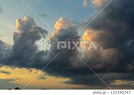 Majestic clouds illuminated by sunset over the horizon with hints of gold and deep blue evening sky 133340747