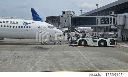 This white passenger jet, bearing the "SKYTEAM" logo, is being pushed back from the airport gate. This white passenger jet, bearing the "SKYTEAM" logo, is being pushed back from the airport gate. 133341054