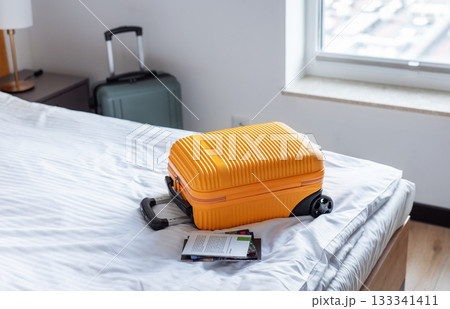 Orange suitcase on hotel bed welcoming travelers arrival 133341411