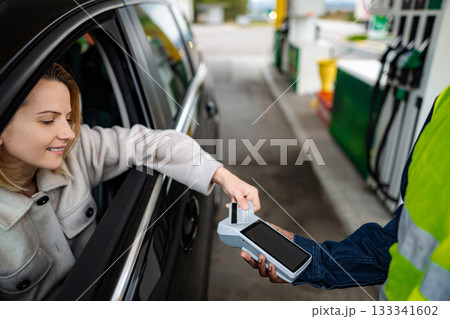 Woman paying for gas fueling car with credit card 133341602