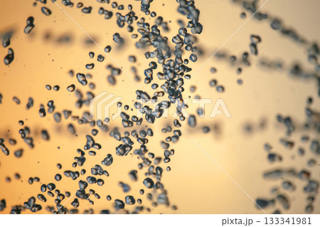 silhouettes of drops falling water fountain against the backdrop of the setting sun 133341981