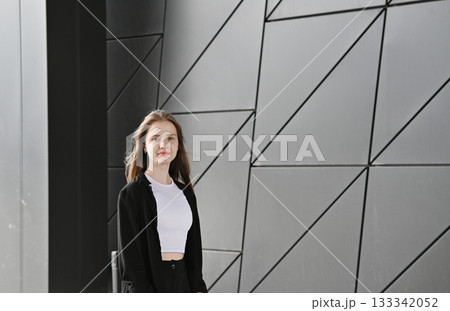 Woman walking near a retractable gate in front of a modern building. Woman walking near a retractable gate in front of a modern building. 133342052