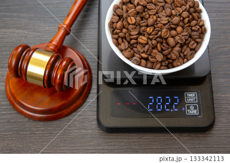 A wooden gavel with a gold band beside a digital scale 133342113