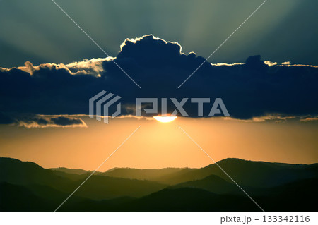 Scenic sunset with the sun peeking through a dark cloud 133342116