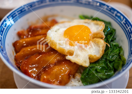 Barbecued red pork in sauce with rice, and fried egg on the top. Barbecued red pork in sauce with rice, and fried egg on the top. 133342201