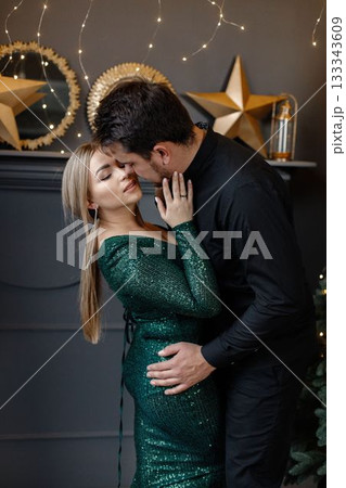 Portrait of young man and woman kissing. Woman touching her husband on a neck. Man wearing black shirt and woman wearing fashion green dress. 133343609