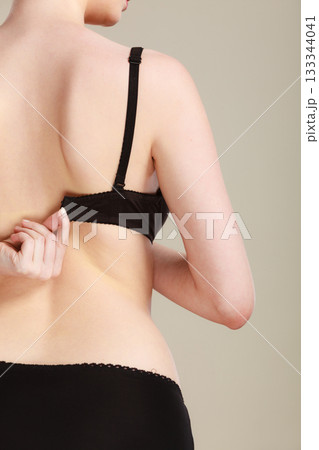 Woman dressing up her bra rear view Woman dressing up her bra rear view 133344041