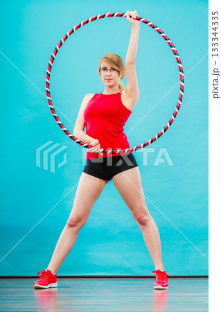 Fit woman with hula hoop doing exercise 133344335