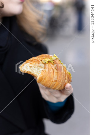 Hand Holding Fresh Pistachio Croissant Outdoors Hand Holding Fresh Pistachio Croissant Outdoors 133344541