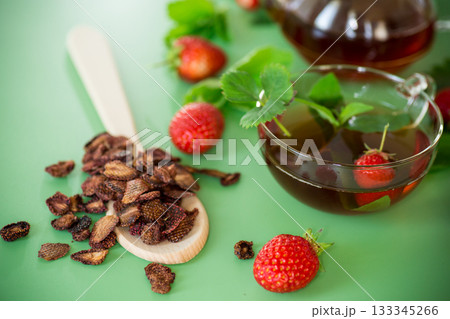 Bright strawberry tea in transparent glassware on a green background 133345266