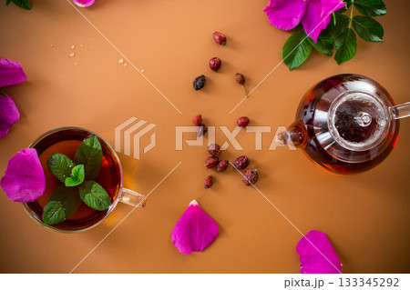 Top view of brewed rosehip tea with mint in glassware on brown background Top view of brewed rosehip tea with mint in glassware on brown background 133345292