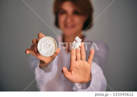 Woman holding skincare cream showing product 133345612