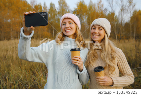 Modern happy women friends taking selfie with phone in park, girlfriends having fun together 133345825