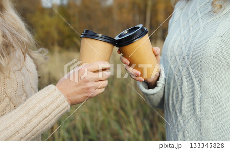 Close up of female hands holding cups of hot coffee drink outdoors 133345828