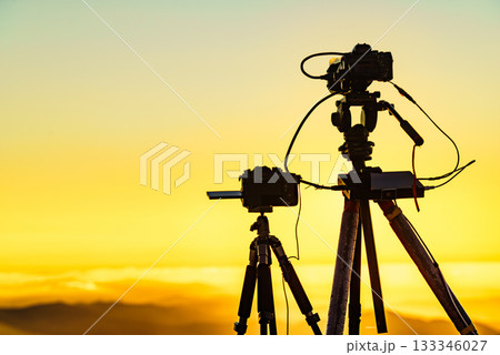 Camera on tripod take photo from sunset above clouds Camera on tripod take photo from sunset above clouds 133346027
