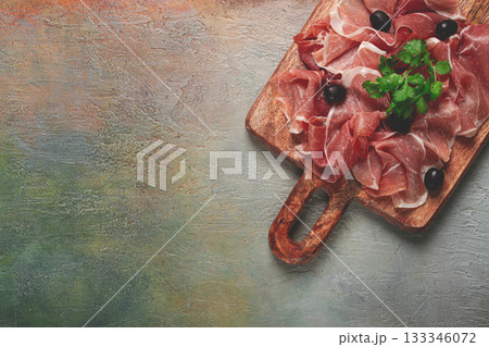 sliced prosciutto, on a cutting board, with olives and herbs, snack, breakfast, no people, 133346072