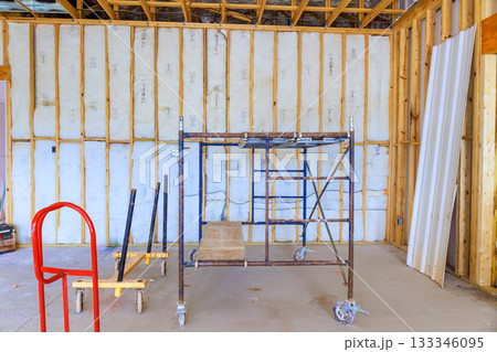 Construction area features scaffolding against wooden walls, awaiting further renovation finishing work. 133346095