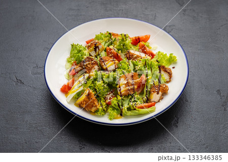 Crispy chicken salad with lettuce, tomatoes, sesame and dressing on plate 133346385