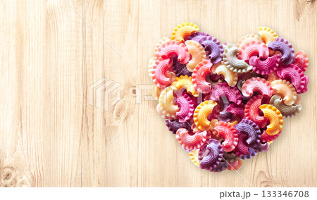 Horizontal banner with Heart formed from uncooked multi-colored pasta on wood texture. Italian food, cuisine, dietary choices, food and love concept. Dried pasta in heart shape. Copy space for text Horizontal banner with Heart formed from uncooked multi-colored pasta on wood texture. Italian food, cuisine, dietary choices, food and love concept. Dried pasta in heart shape. Copy space for text 133346708