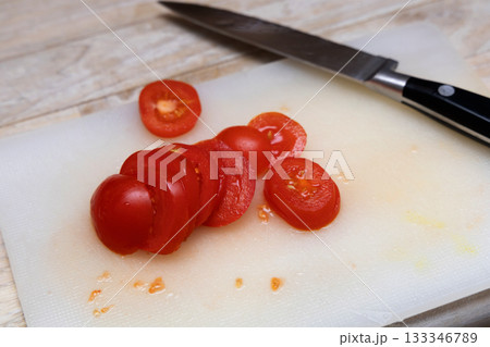 Small tomato chopped on synthetic cutting surface. Small tomato chopped on synthetic cutting surface. 133346789