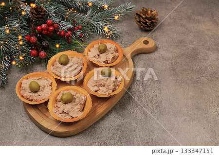 A tray of tartlets with pate, cheese, and olives on a concrete table,a Christmas Eve concept. Christmas and New Year's dishes, a selection of appetizers and treats for the festive table. A tray of tartlets with pate, cheese, and olives on a concrete table,a Christmas Eve concept. Christmas and New Year's dishes, a selection of appetizers and treats for the festive table. 133347151