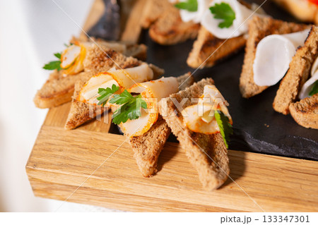 Delicious Appetizer Served on a Wooden Platter With Fresh Herbs and Seafood 133347301