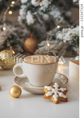 Cup of Hot Coffee with Christmas Gingerbread Cookies and Ornaments in Festive Setting 133347329
