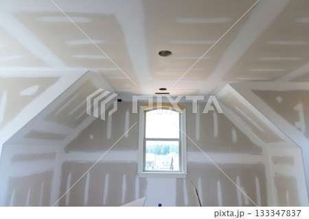 Newly renovated room bare drywall waiting for finishing touches, with space during painter Newly renovated room bare drywall waiting for finishing touches, with space during painter 133347837