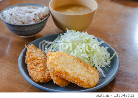 フライと千切りキャベツ、雑穀ごはんと味噌汁の家庭的な昼食 133348512